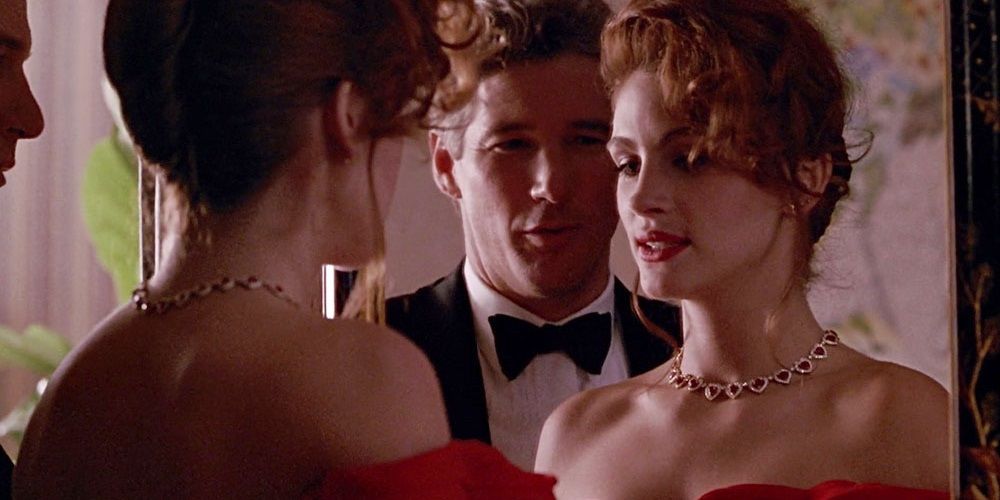 Edward stands behind Vivian as she looks in a mirror in Pretty Woman