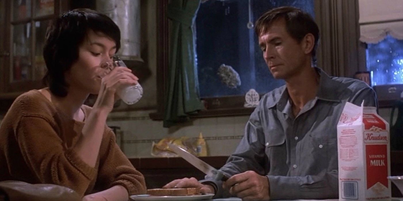 Norman looks at a knife while a lady drinks milk in Psycho II.