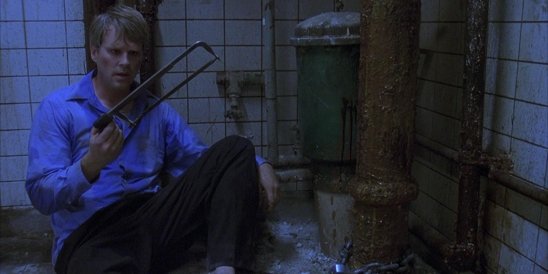 Cary Elwes como el Dr. Lawrence Gordon contemplando qué hacer con una sierra para metales en la película de terror de 2004 Saw.