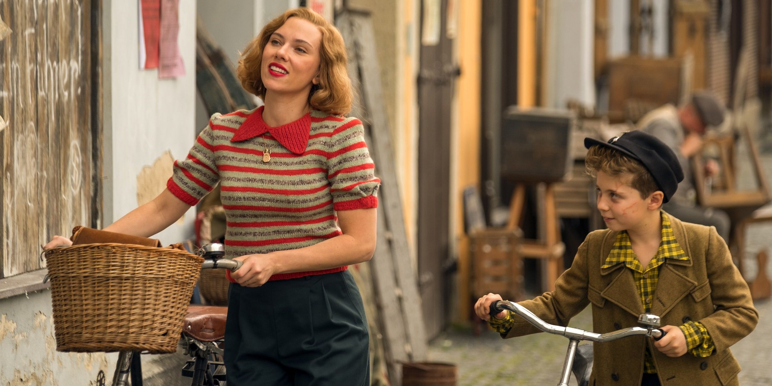 Rosie (Scarlett Johansson) and Jojo (Roman Griffin Davis) walking with their bikes in Jojo Rabbit