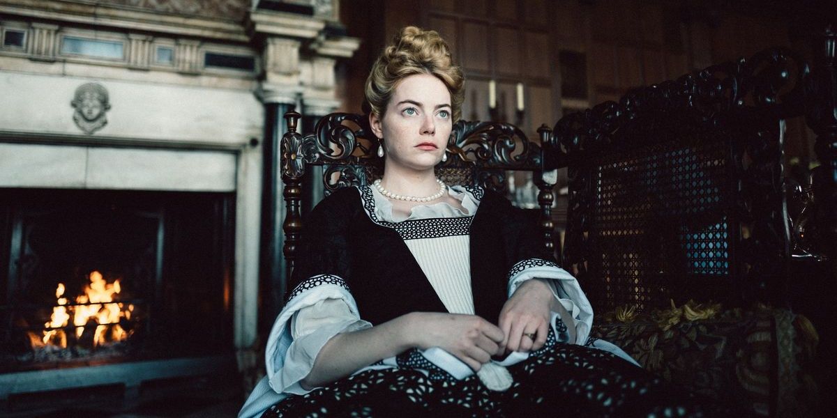 Emma Stone in period dress sitting in a chair in The Favourite.