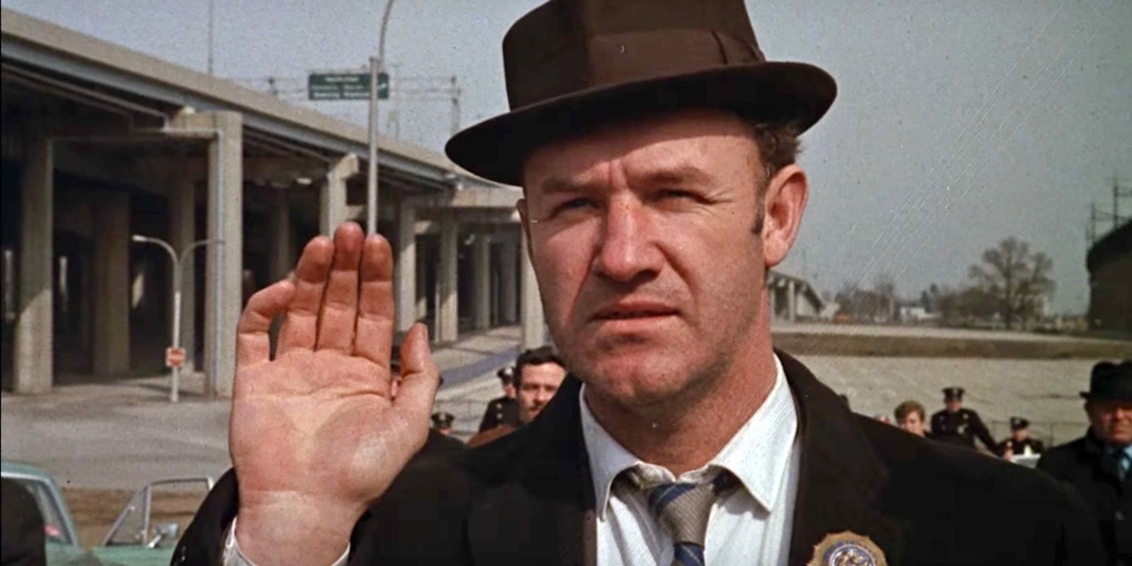 Gene Hackman as cop Popeye Doyle waving in The French Connection
