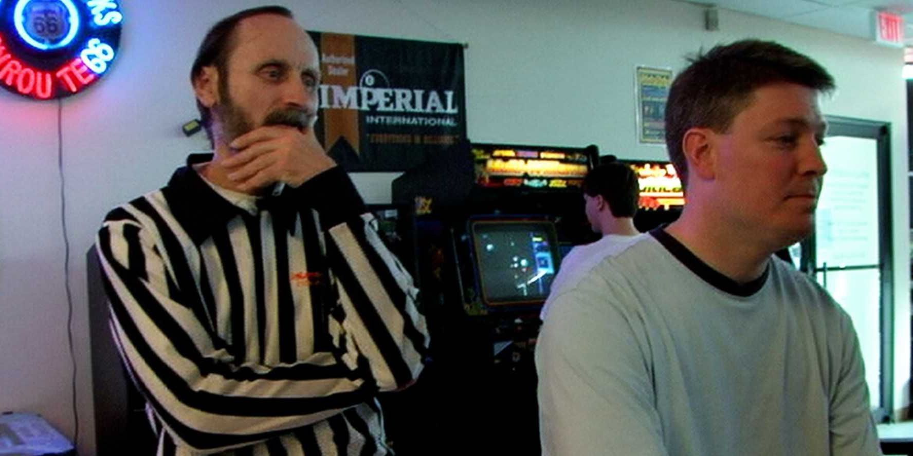 A referee watches a player in an arcade in The King of Kong 