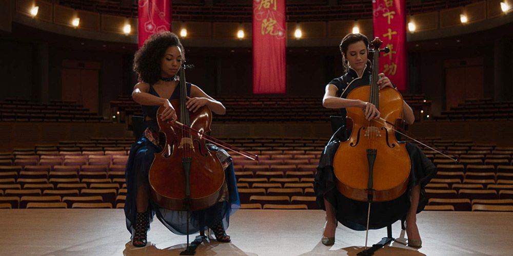 Charlotte and Lizzie playing violin on stage in The Perfection