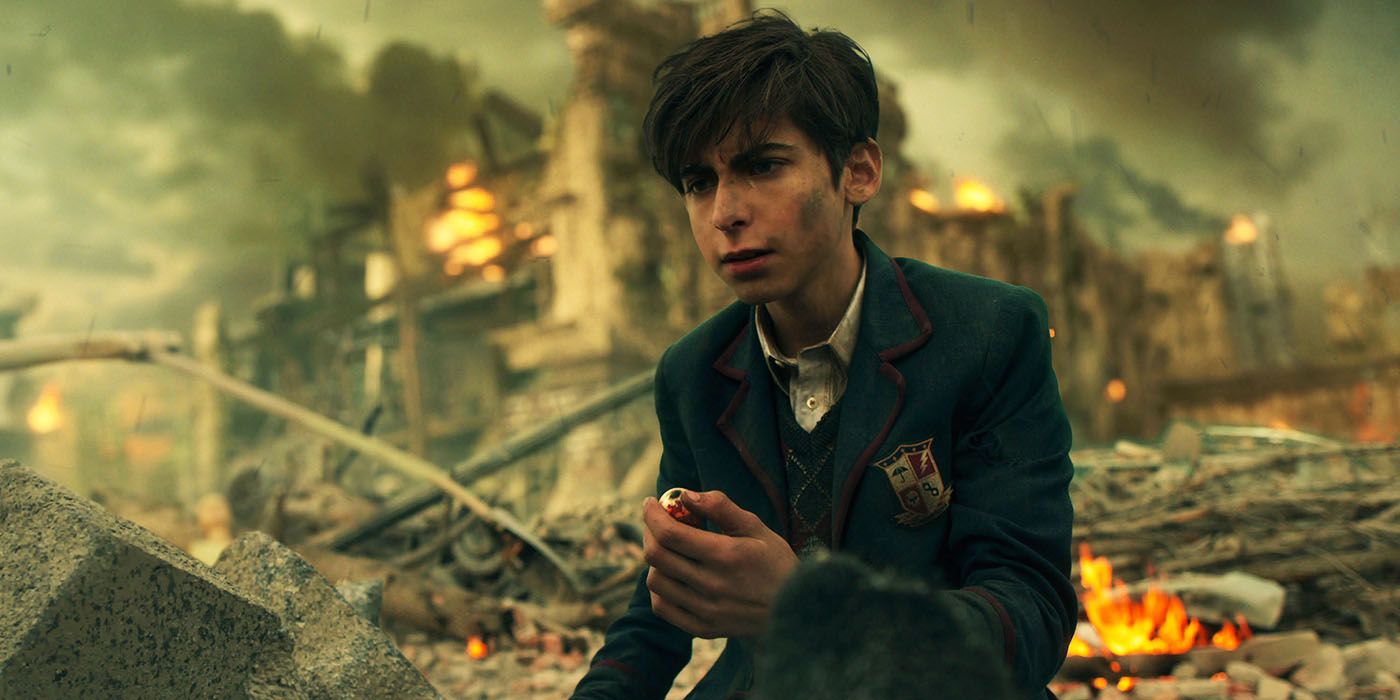 Aidan Gallagher as Number Five sitting among the fiery ruins of the world in The Umbrella Academy season 1