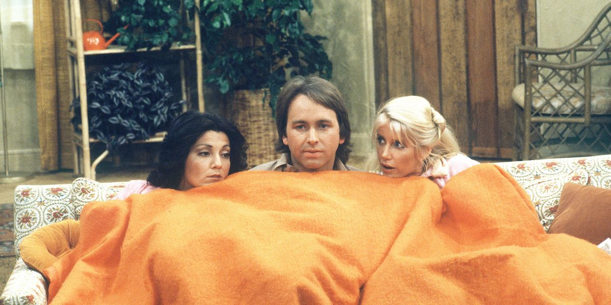 The Three's Company cast under a blanket.