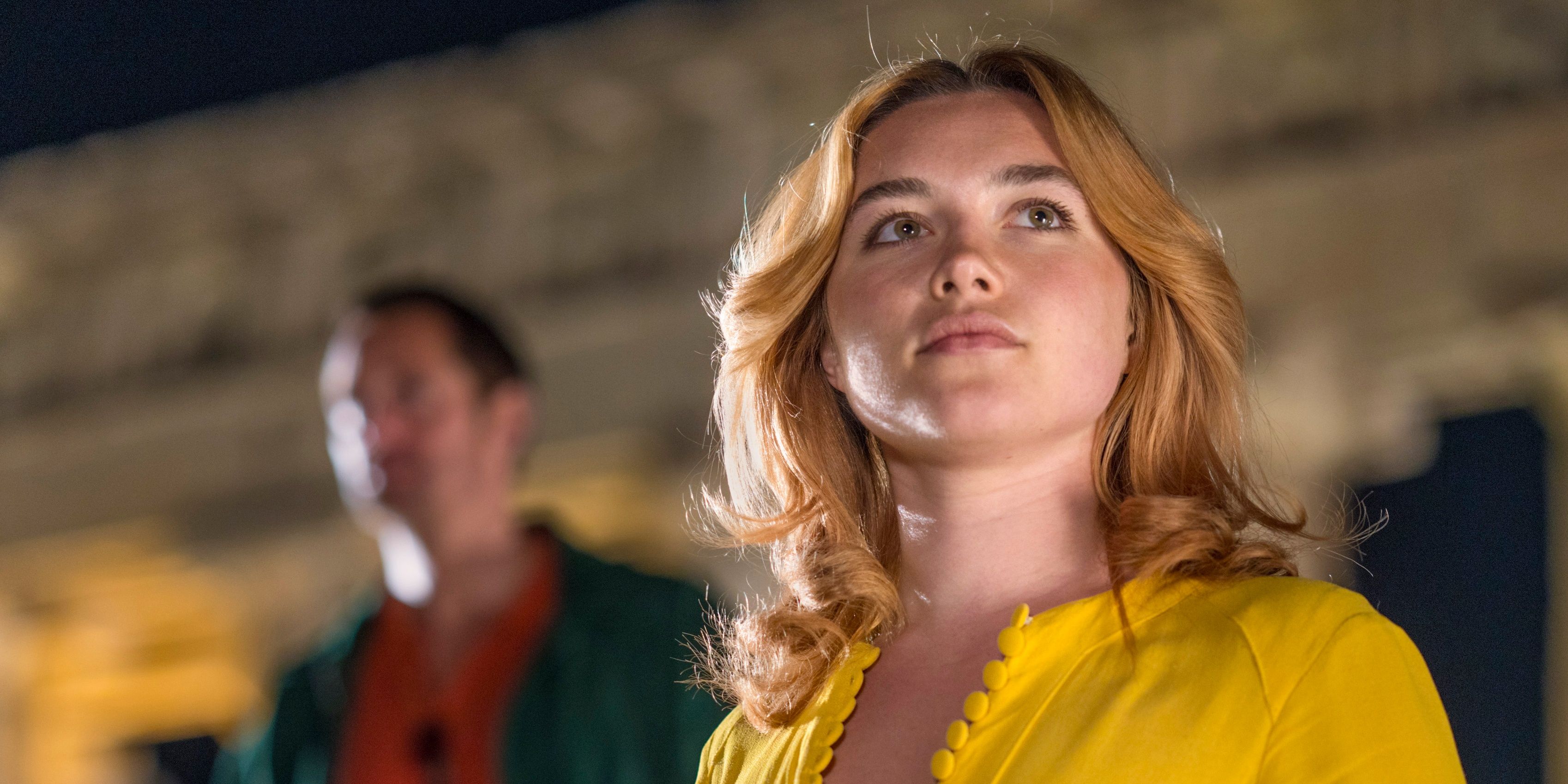Florence Pugh in The Little Drummer Girl looks up and off camera in a yellow shirt.