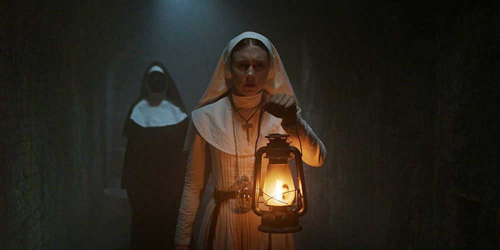Sister Irene holding a lantern with a faceless nun behind her in The Nun 2018
