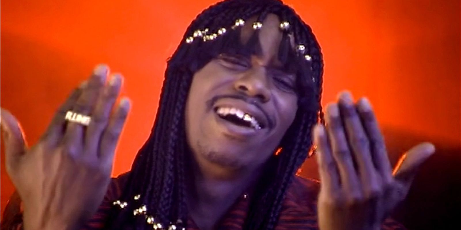 Dave Chappelle with his hands up and his hair in beaded braids in Chappelle's Show.