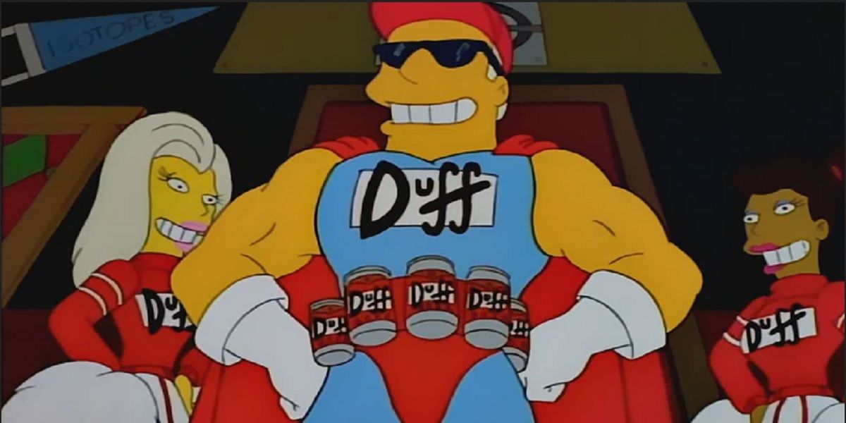 Duffman confidently stands between two cheerleaders and wearing a belt made of beers