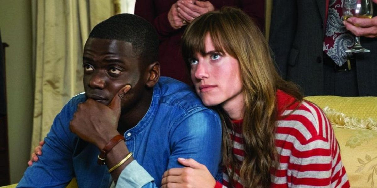 A man and a woman sitting on the couch and looking up in Get Out.