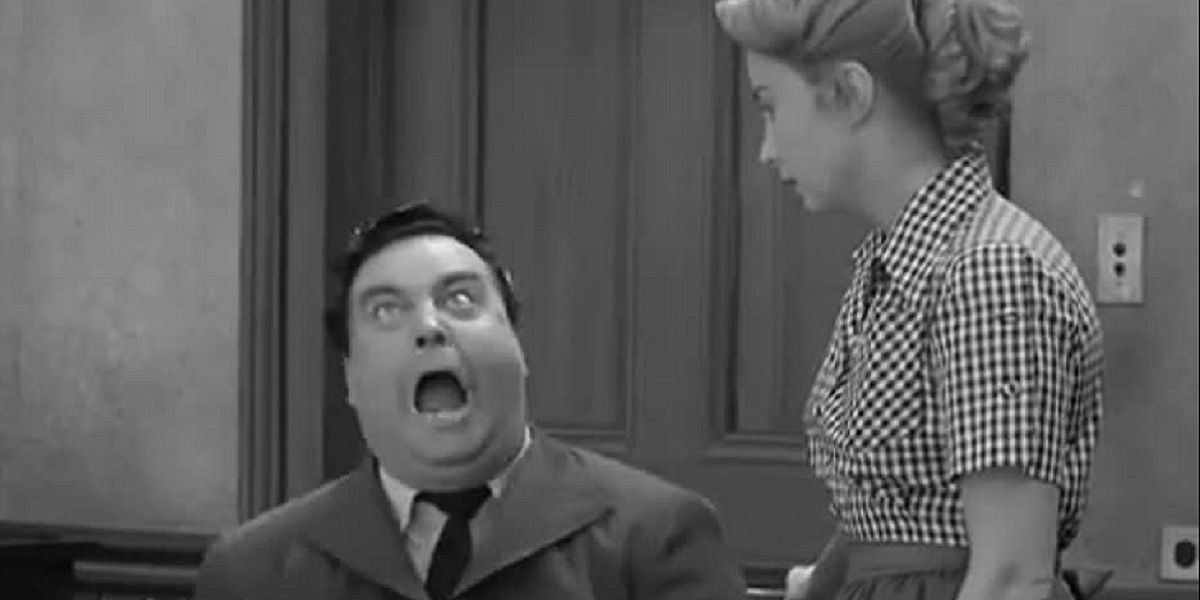 Ralph Kramden (Jackie Gleason) shouts angrily at the kitchen table while his wife Alice (Audrey Meadows) watches patiently