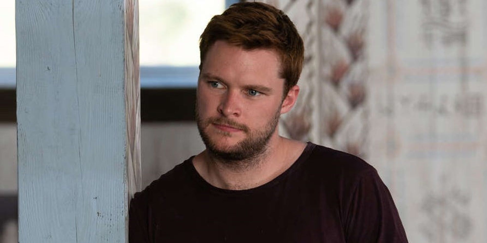 Jack Reynor leans against a wall and listens in Midsommar
