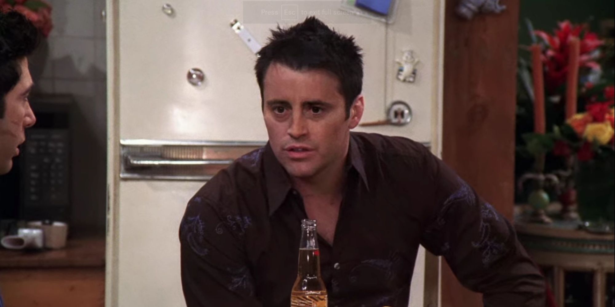 Joey sentado na cozinha de Monica e Rachel em Friends
