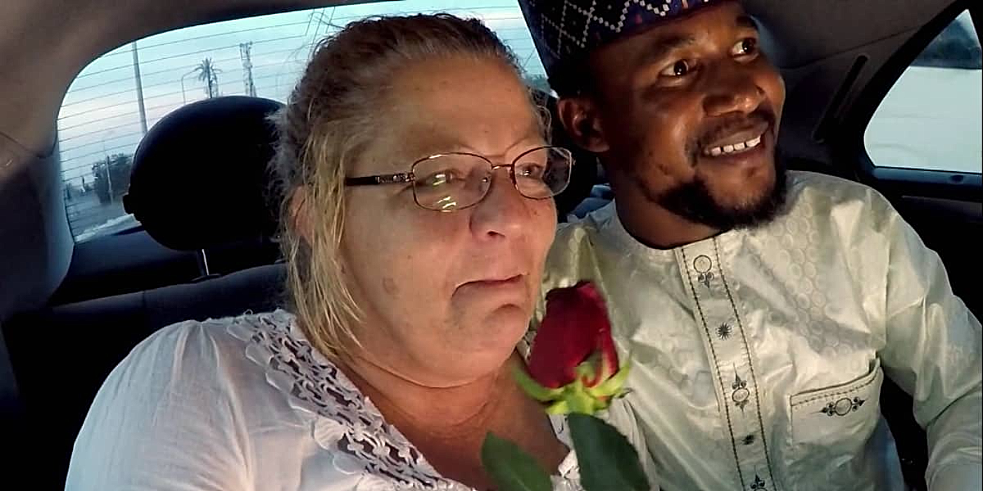 Lisa Hamme and Usman Umar from 90 Day Fiancé- Before the 90 Days sitting in the backseat of a car wearing white outfits and Lisa smiles, holding a red rose