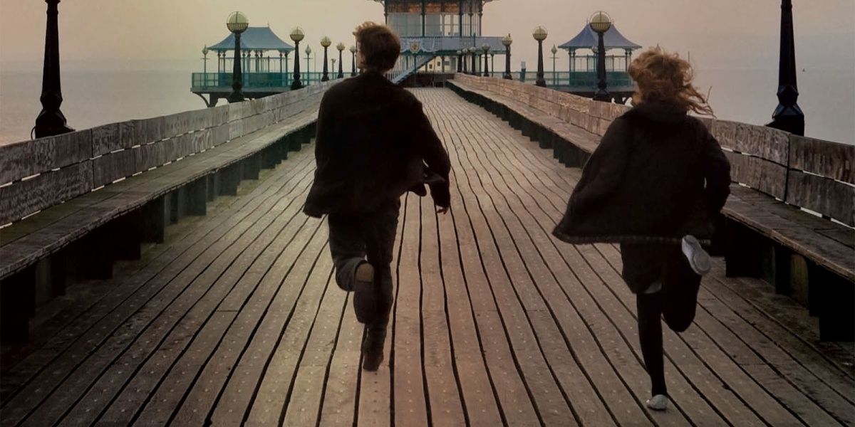 Main characters running away from the camera on the boardwalk in Never Let Me Go