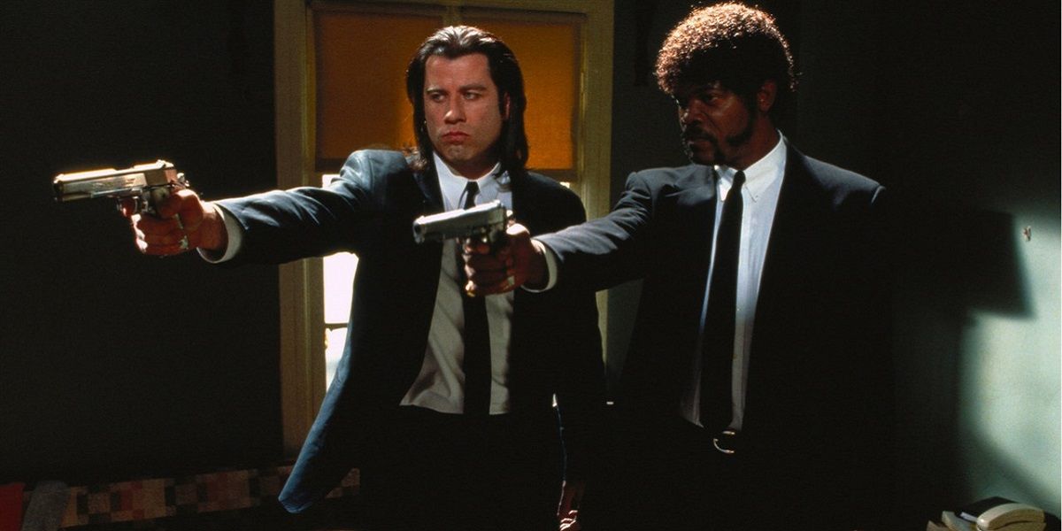 Two men in suits pointing their guns towards someone offscreen in Pulp Fiction.