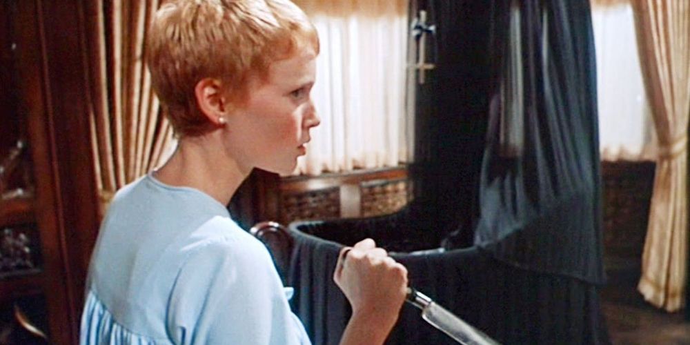 Rosemary standing beside a crib while holding a knife in Rosemary's Baby.