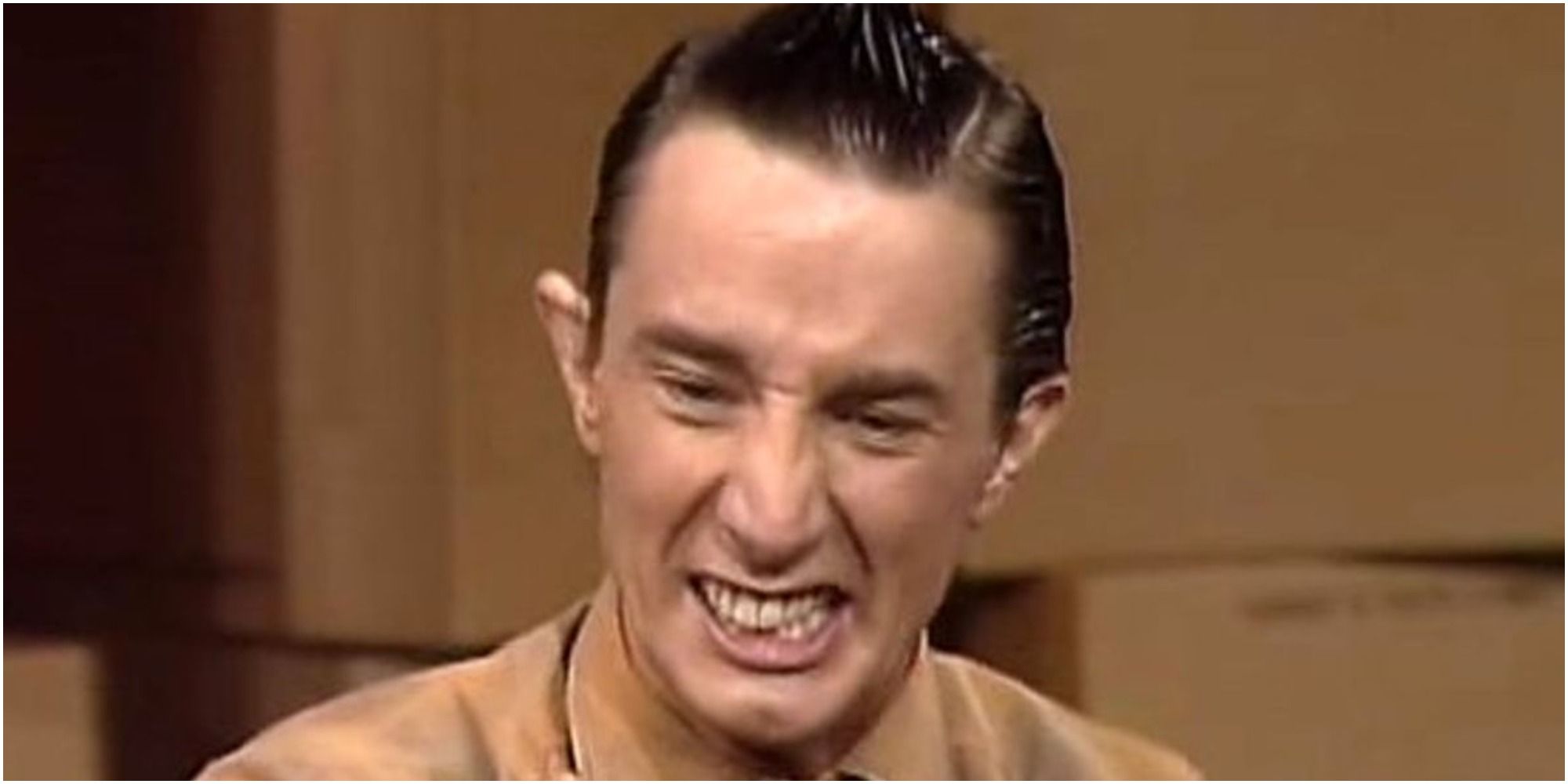 Martin Short playing Ed Grimley in 'The Contestant' sketch on SNL, making an awkward smile with spiked up hair