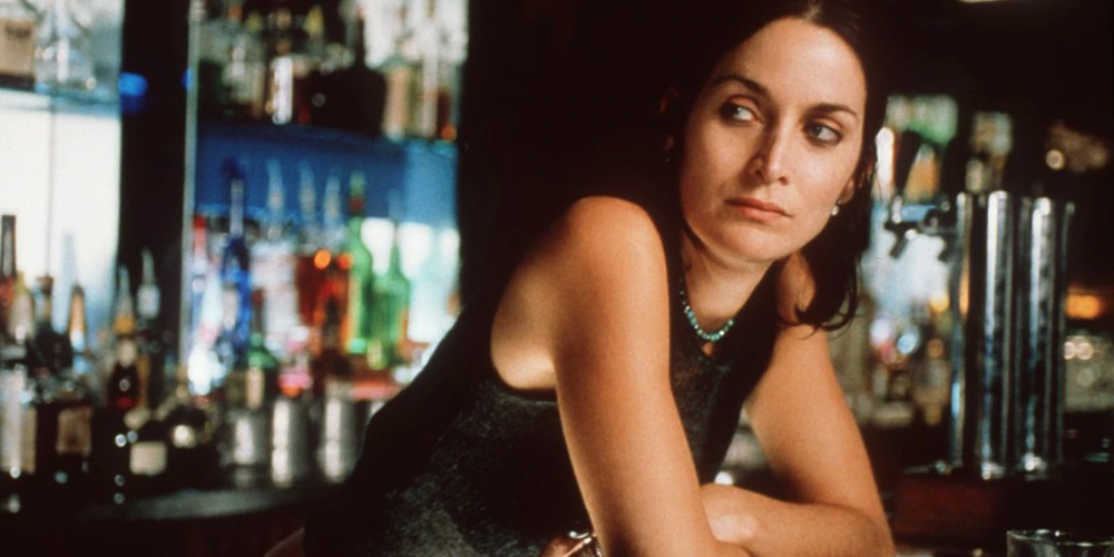Natalie leans over a bar in Memento
