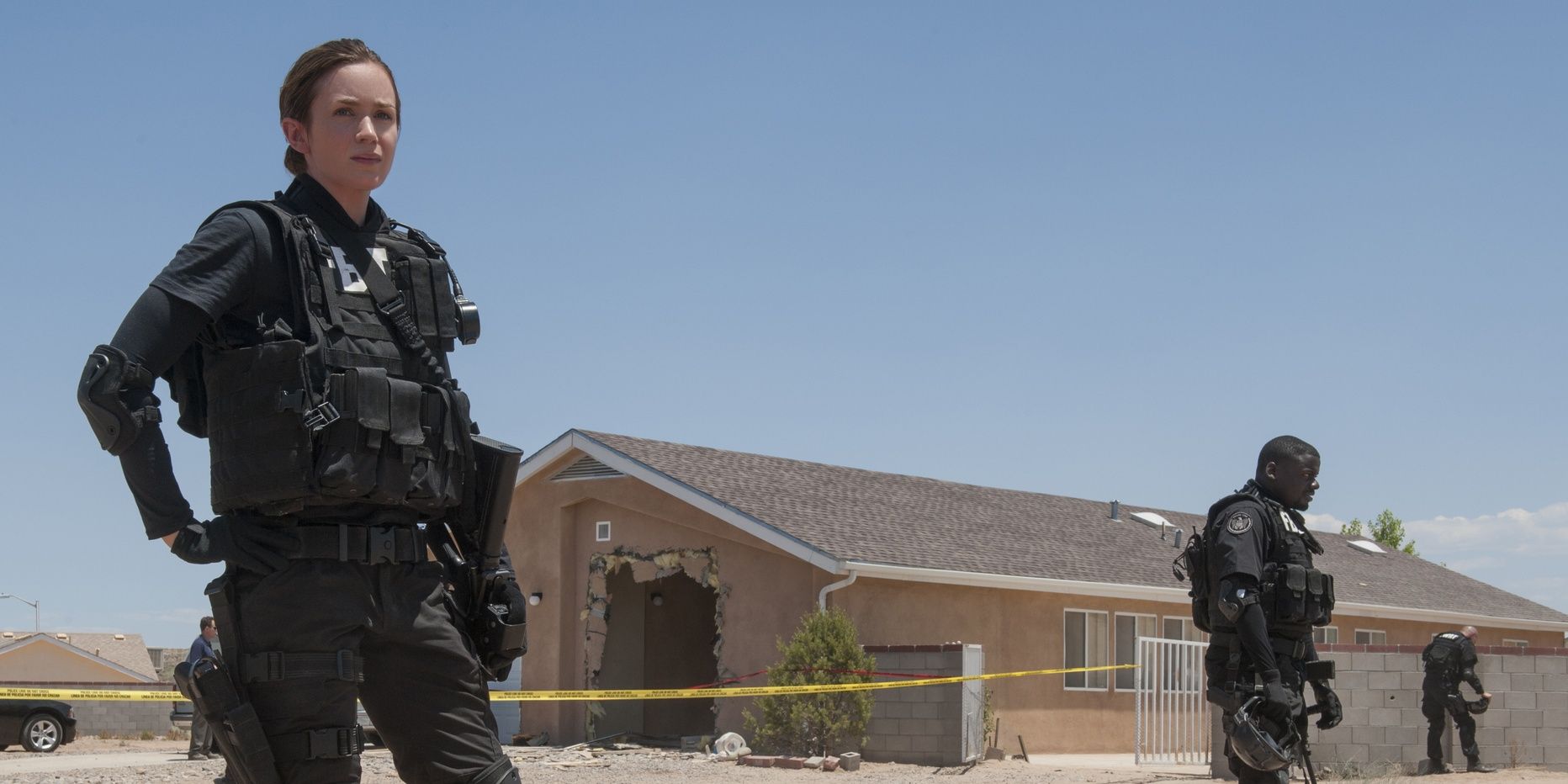 Emily Blunt standing in front of a house in uniform in Sicario.