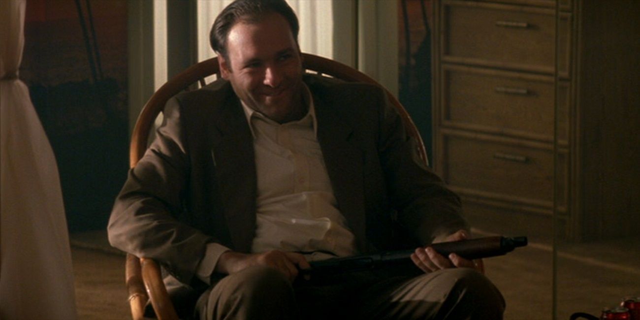 Virgil sits on a chair holding a machine gun in True Romance
