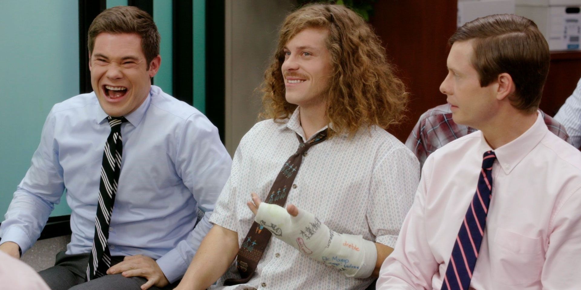 Three work buddies laughing and smiling in Workaholics 