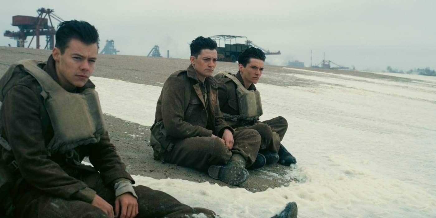 Harry Styles as a solder in Dunkirk sitting on the beachside with other soldiers 