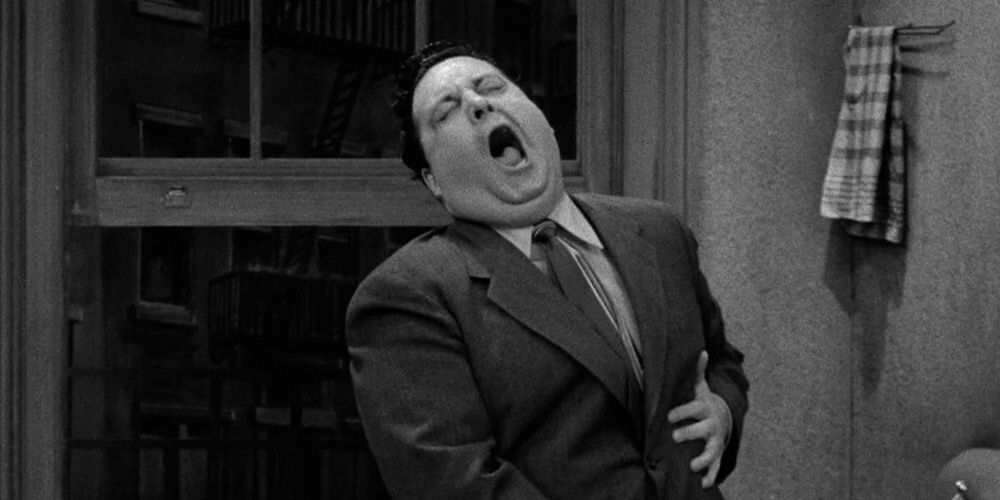 Jackie Gleason as Ralph Kramden holding his stomach and crying out in pain
