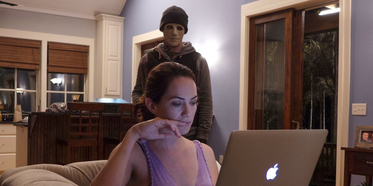 Scene from Hush with woman on computer and man standing behind her.