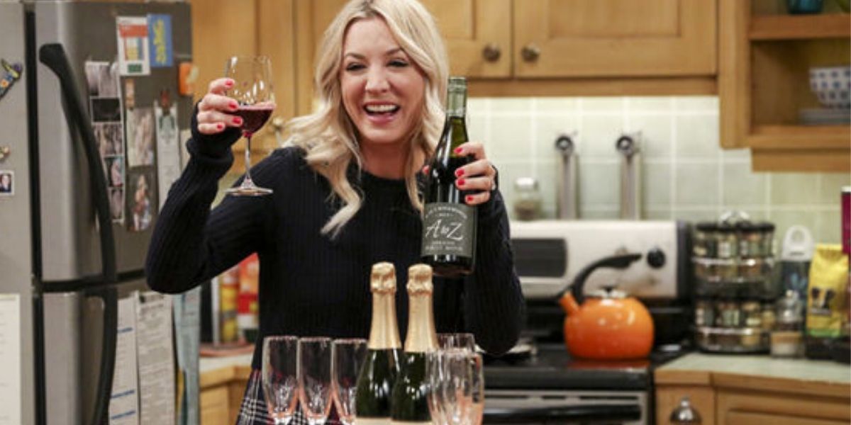 Penny smiling and holding up wine on the big bang theory