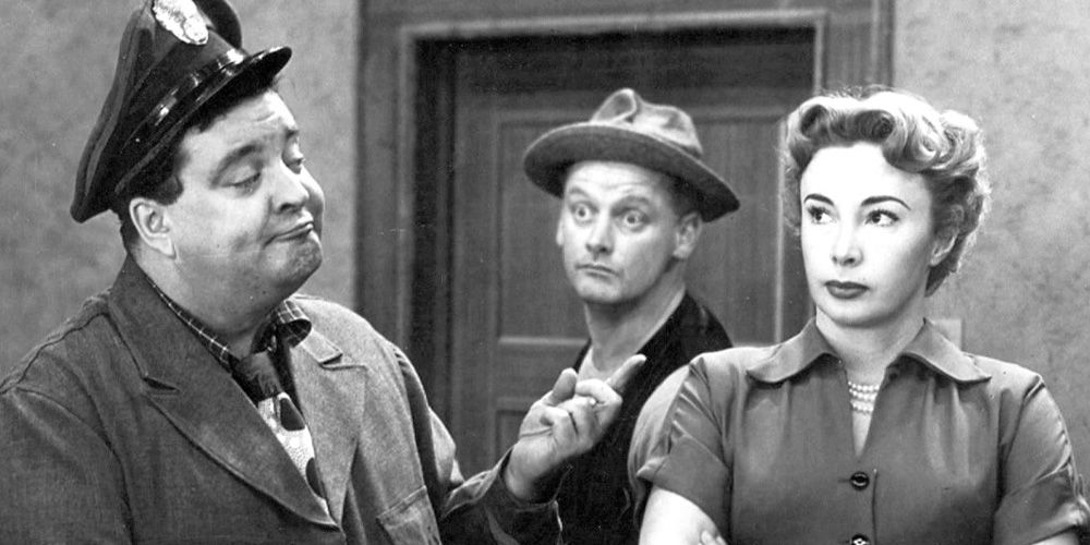 Jackie Gleason as Ralph Kramden, pointing at Alice (Audrey Meadows) while Ed Norton (Art Carney) sticks his head in between the two