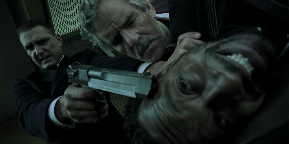 Vinnie Jones puts a gun to Lennie James' head as Denis Farina watches in Snatch
