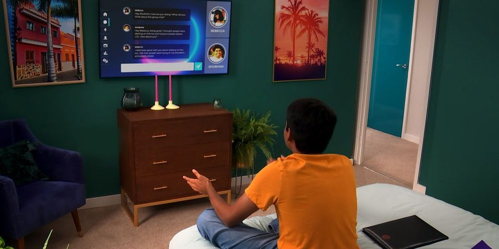 A contestant sitting on his bed in front of a TV in The Circle.