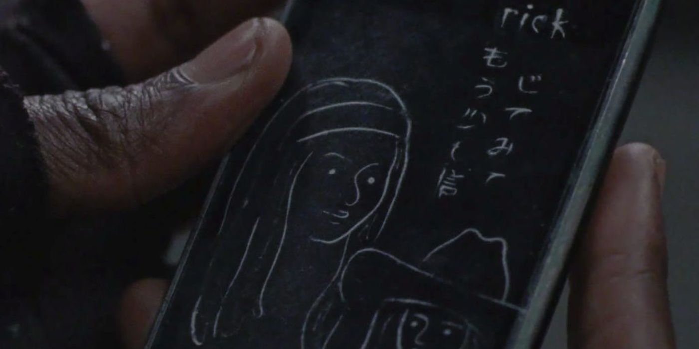 Michonne holding a cell phone with Japanese writing on it and drawings of her and Judith