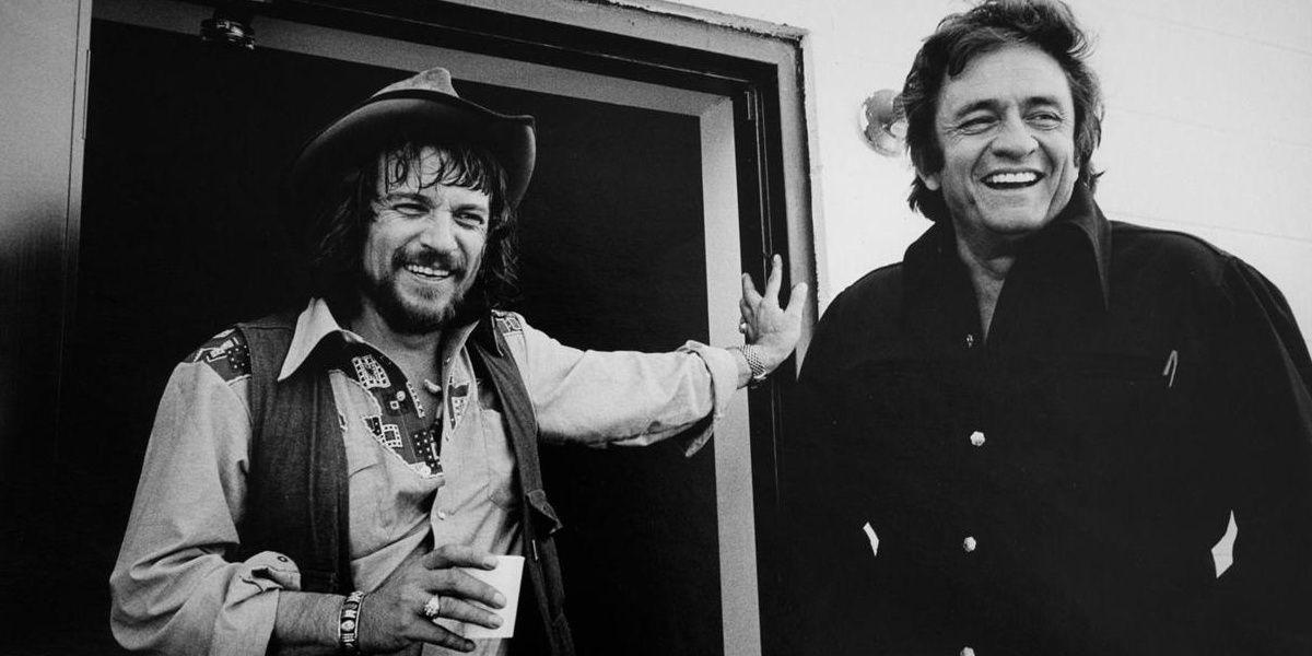 Johnny Cash smiling and posing with Waylon Jennings