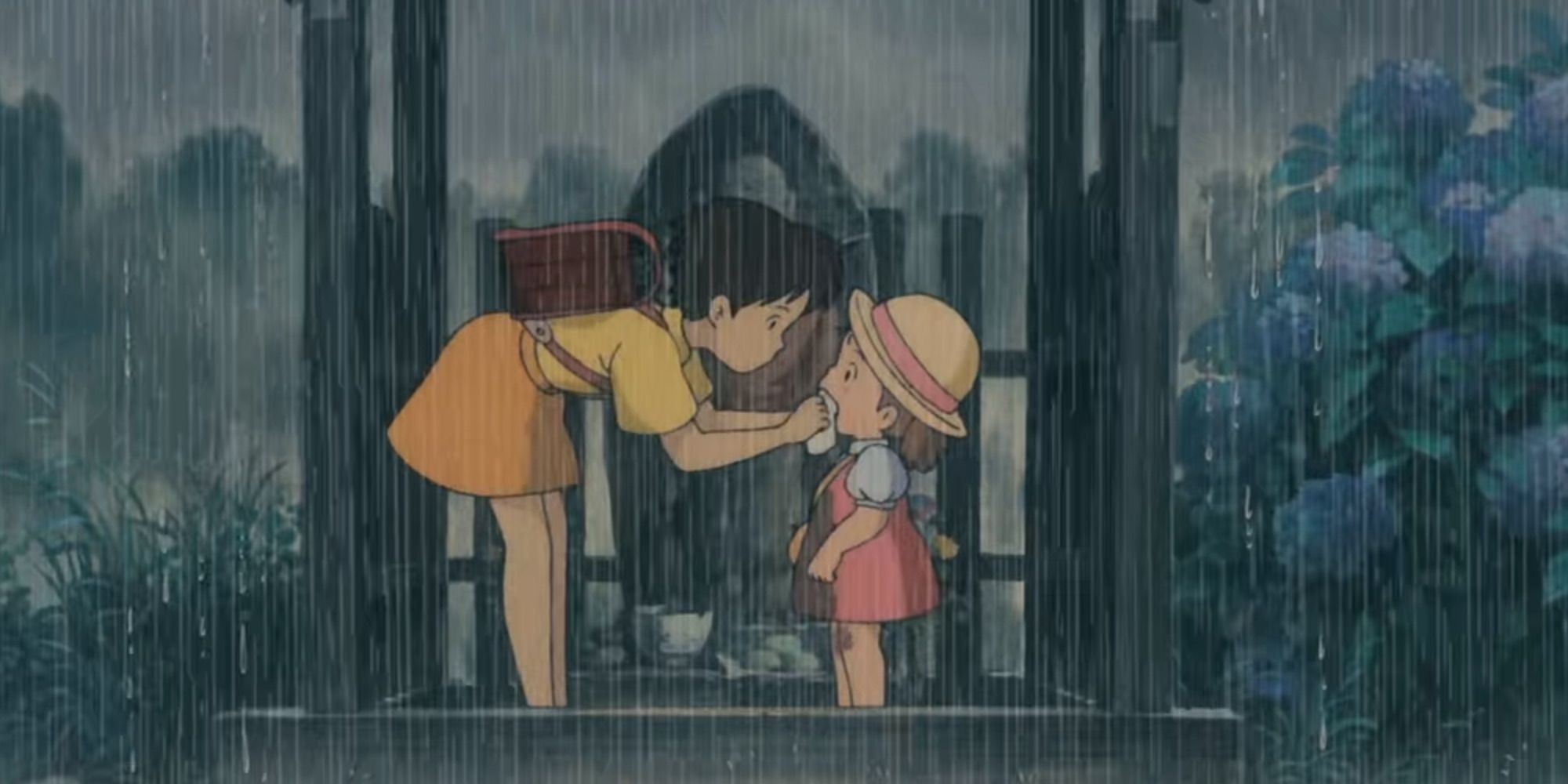Mei e Satsuki se protegem da chuva em um santuário à beira da estrada em My Neighbor Totoro
