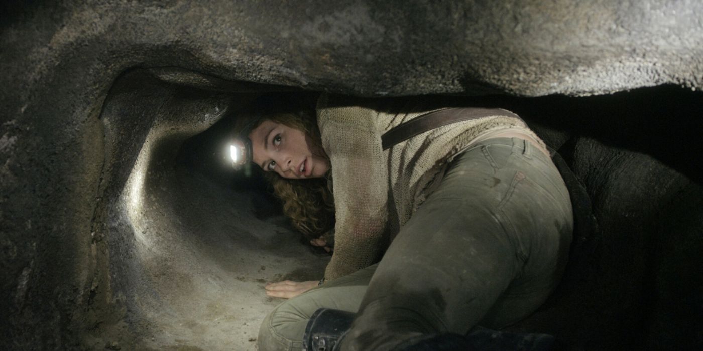 A woman crawls through a rock in As Above So Below
