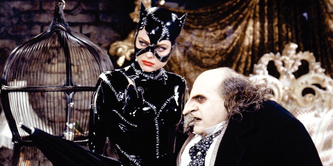 Catwoman and Penguin look to the side with a bed in the background in Batman Returns.