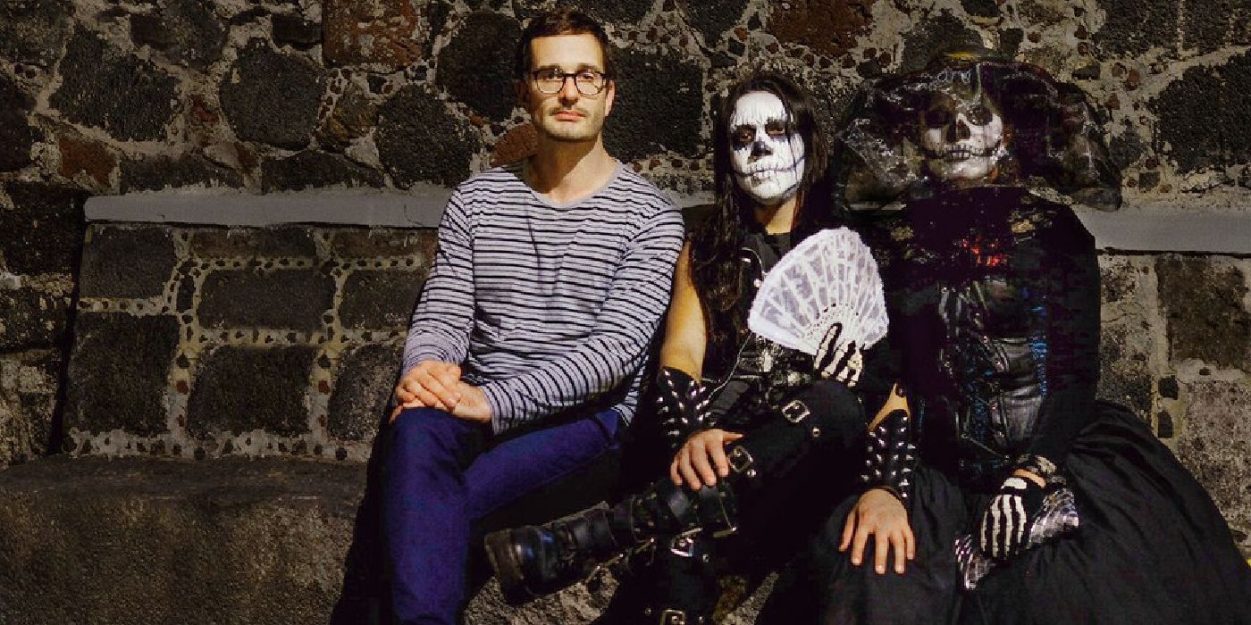 A man sitting next to a couple in skull makeup in Dark Tourist