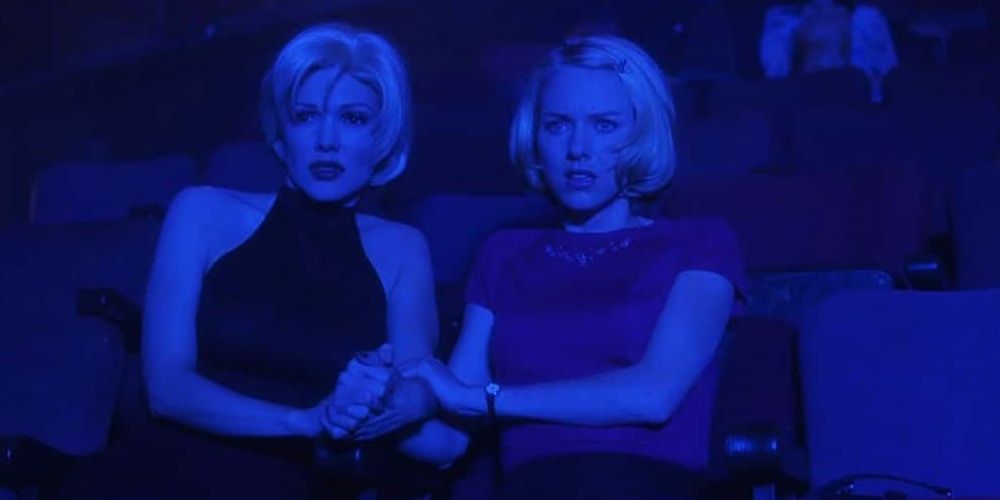 Rita and Betty holding hands at a theater covered in blue light in Mulholland Drive.