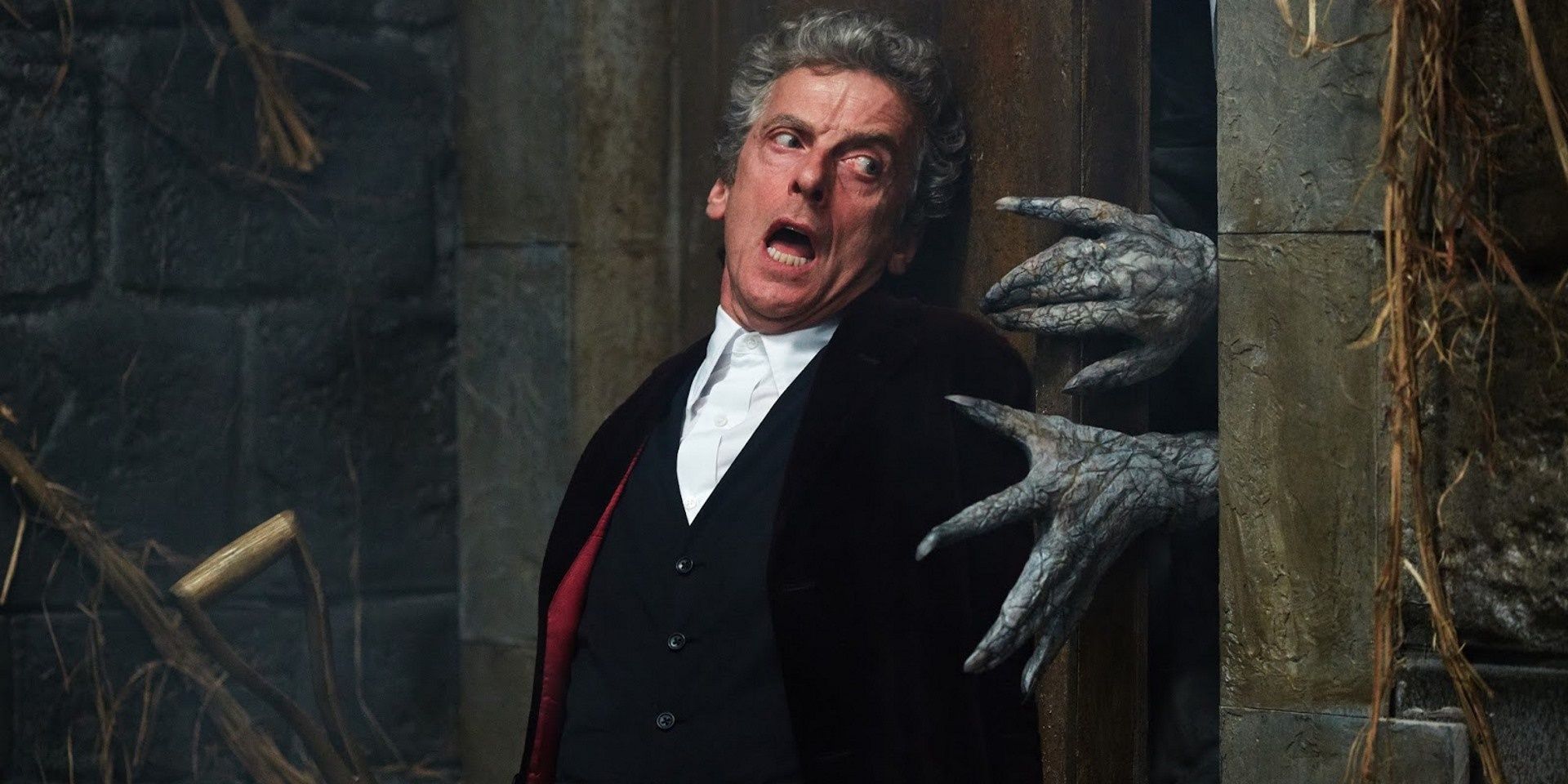 The Twelfth Doctor putting pressure on the door to keep out the veiled monster 