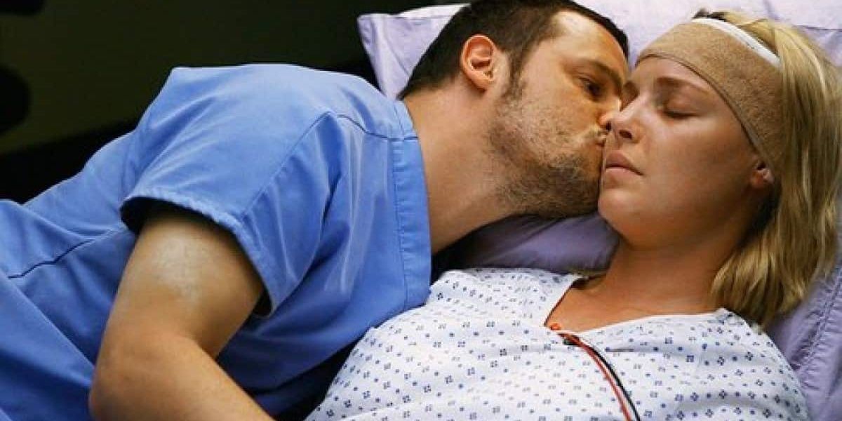 Alex kissing Izzie on the cheek while she lies in a hospital bed on Grey's Anatomy