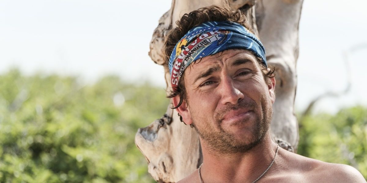 Close-up of J.T. grimacing with his back against a tree on Survivor