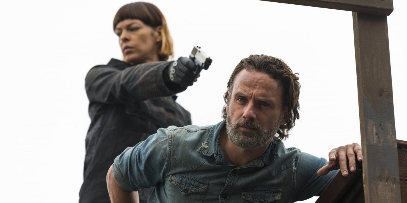 Jadis aims a gun at Rick, who is looking down at something, in The Walking Dead