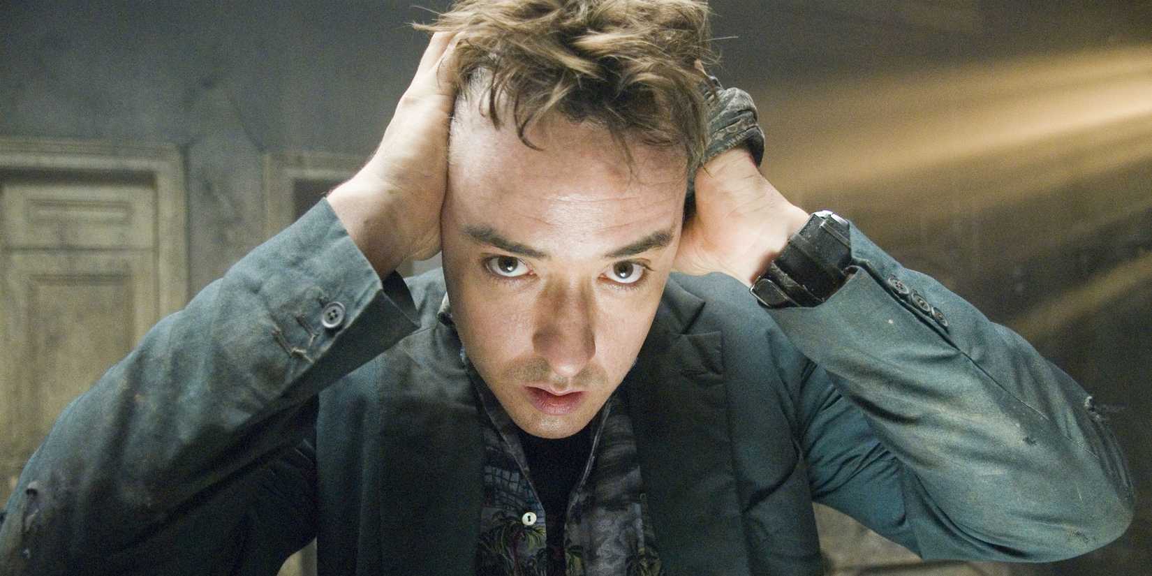 John Cusack as Mike Enslin holding his head and looking distraught in 1408