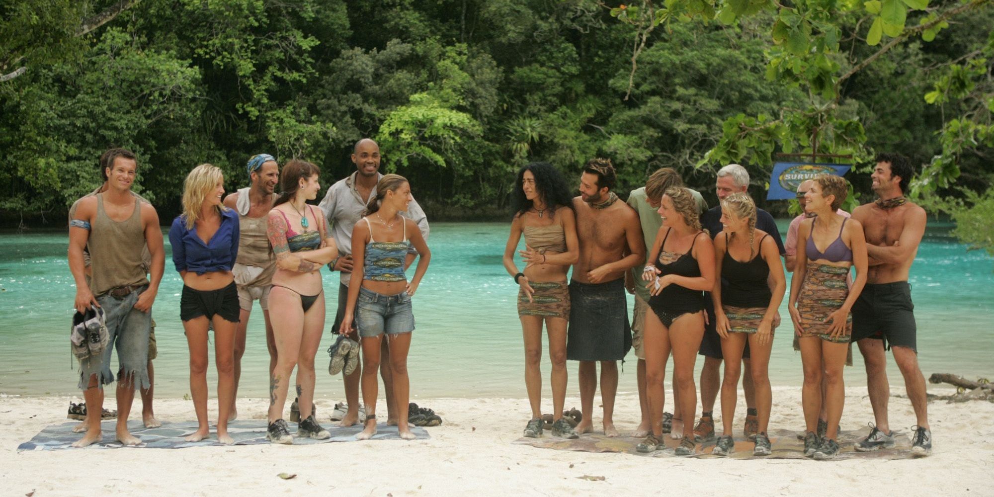 Two teams stand around on a beach in Survivor.