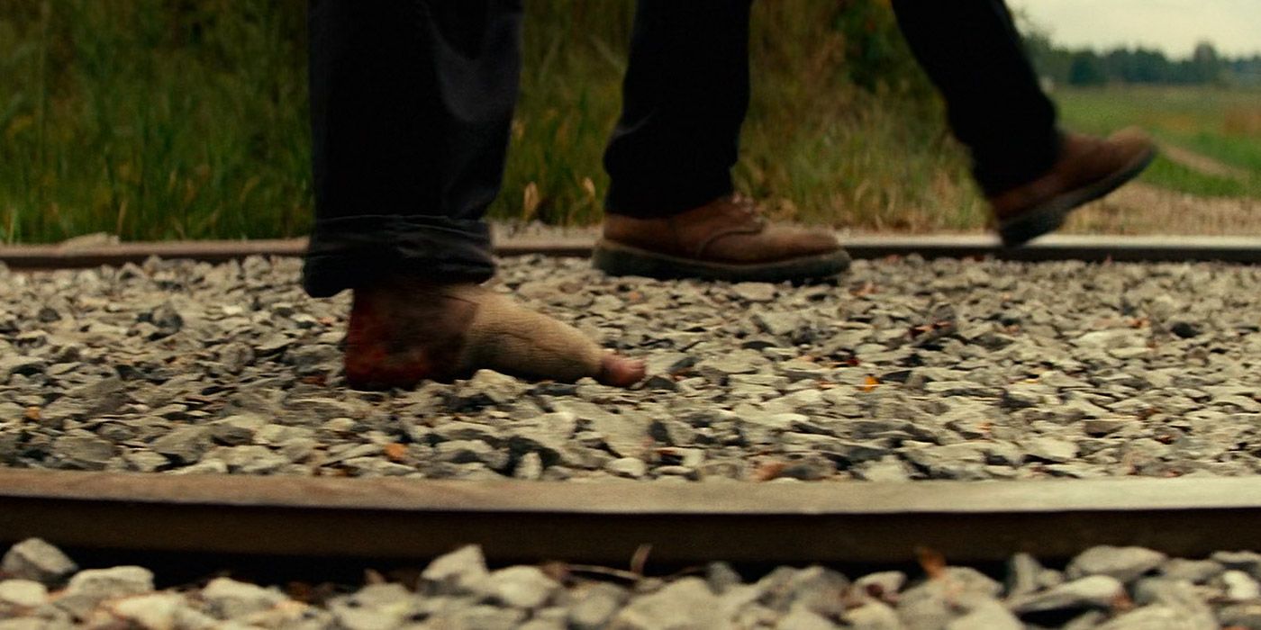 Regan and Emmett walking on train tracks in A Quiet Place II