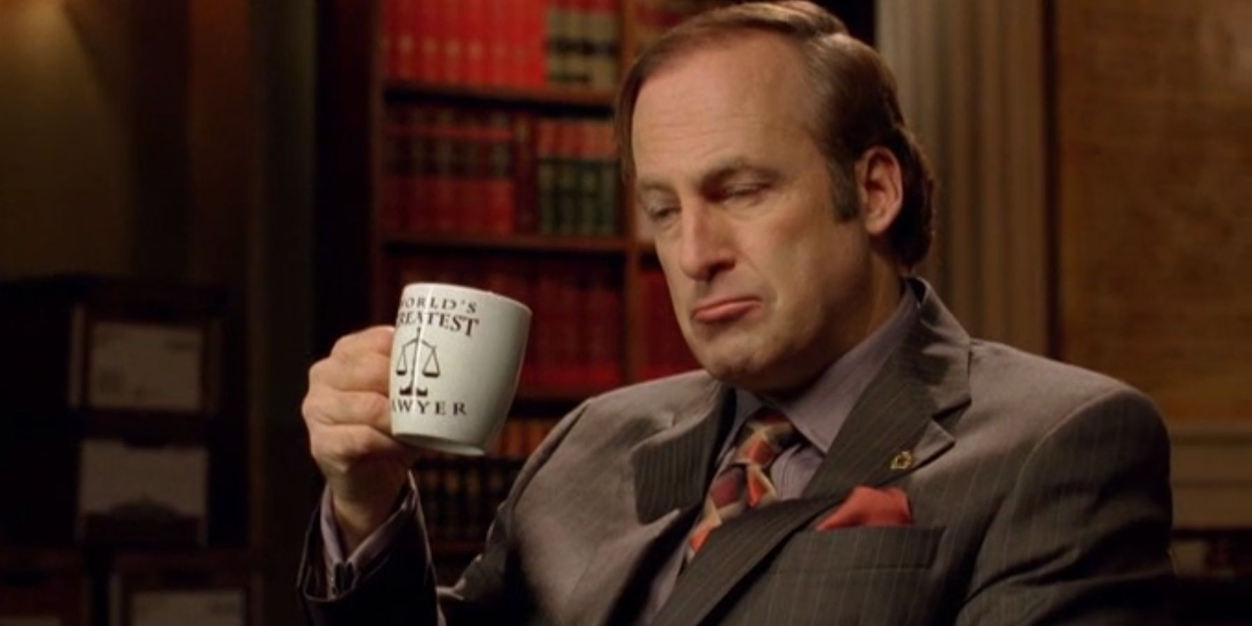 Saul Goodman sips coffee as he listens to Jesse talk about cutting off Walt in Breaking Bad
