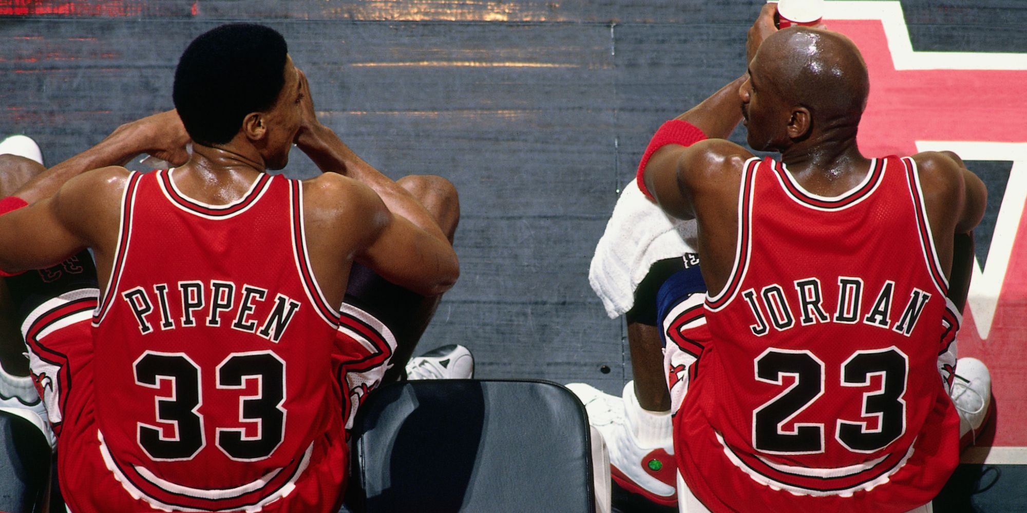 Michael Jordan and Scottie Pippen look at one another while sitting down.